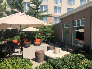 un patio con mesas, sillas y una sombrilla en Hilton Garden Inn Addison, en Addison