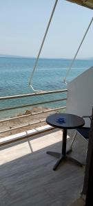 een tafel en een stoel op een balkon met uitzicht op de oceaan bij Christinas 1 in Nerántza