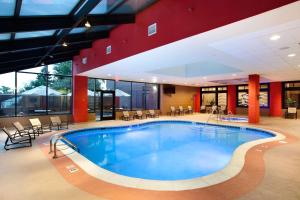 Hilton Suites Chicago/Oakbrook Terrace في أوكبروك تراس: مسبح كبير في فندق به طاولات وكراسي