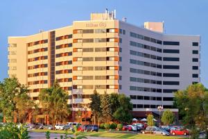 un edificio de hotel con coches aparcados en un aparcamiento en Hilton Suites Chicago/Oakbrook Terrace, en Oakbrook Terrace