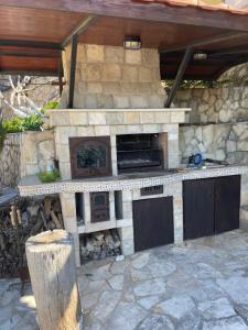 an outdoor kitchen with a stone fireplace in a patio at Семейный комплекс для отдыха in Pečurice
