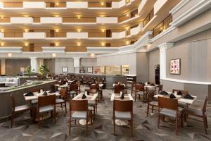 Hilton Suites Chicago/Oakbrook Terrace في أوكبروك تراس: منطقة طعام مع طاولات وكراسي في مطعم