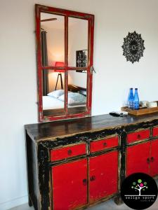 a red dresser with a mirror on top of it at Seliga Sport Apartments & SPA in Lesznowola