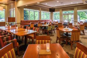 a restaurant with wooden tables and chairs and windows at Hilton Garden Inn Charlottesville in Charlottesville
