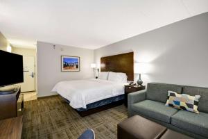 a hotel room with a bed and a couch at Hampton Inn Chicago-Naperville in Naperville