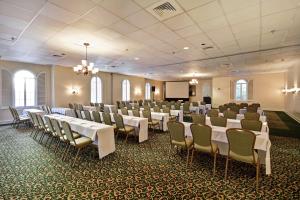 een feestzaal met witte tafels en stoelen en een scherm bij Embassy Suites Charleston - Historic District in Charleston