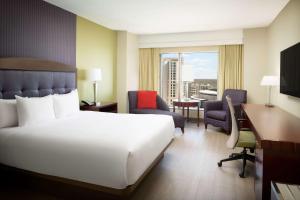 um quarto com uma grande cama branca e uma secretária. em Hilton Charlotte Uptown em Charlotte