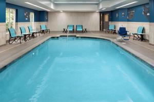 a large swimming pool with blue chairs and tables at Hilton Garden Inn Charlotte/Mooresville in Mooresville