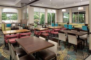 un restaurante con mesas, sillas y ventanas en Hilton Garden Inn Charlotte/Mooresville en Mooresville