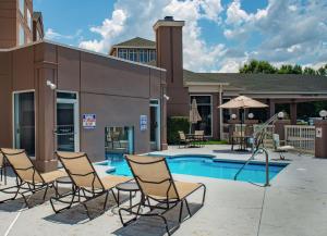 a group of chairs sitting around a swimming pool at Hilton Garden Inn Charlotte Pineville in Charlotte