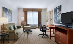 シャーロットにあるHilton Garden Inn Charlotte Pinevilleのデスクとリビングルームが備わるホテルルームです。