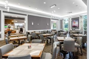 Hilton Columbus at Easton في كولومبوس: مطعم بطاولات وكراسي خشبية ونوافذ