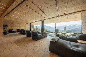 una sala de estar con sofás de cuero y ventanas grandes. en DAS GERSTL Alpine Retreat, en Malles Venosta