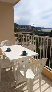 Biały stół i krzesła na balkonie w obiekcie Studio avec coin nuit 150m de la plage w mieście Le Lavandou