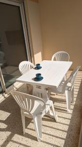- une table et des chaises blanches sur la terrasse dans l'établissement Studio avec coin nuit 150m de la plage, au Lavandou