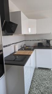 uma cozinha com armários brancos e um balcão preto em Studio avec coin nuit 150m de la plage em Le Lavandou