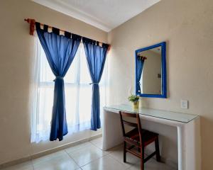 a room with a window with blue curtains and a mirror at Bungalows Las Hamacas in San Patricio Melaque