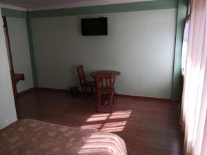 een kamer met een tafel en twee stoelen en een televisie bij Cruz Popayan Sucre in Sucre