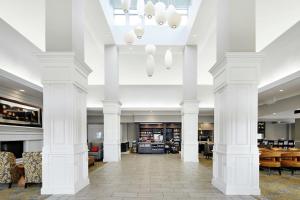 a lobby with white columns and tables and chairs at Hilton Garden Inn Champaign/ Urbana in Champaign