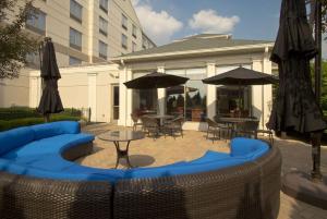 un patio con sillas azules, mesas y sombrillas en Hilton Garden Inn Columbus-University Area en Columbus