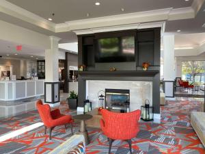 a lobby with a fireplace and red chairs at Hilton Garden Inn Columbia in Columbia