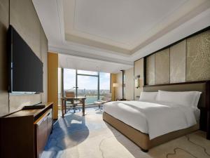 a bedroom with a large bed and a television at Hilton Zhuzhou in Zhuzhou