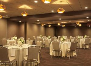 uma sala de banquetes com mesas e cadeiras brancas em The Broadway Columbia - a DoubleTree by Hilton Hotel em Columbia