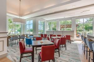 un restaurante con mesas, sillas y ventanas en Hilton Garden Inn Cincinnati/Sharonville, en Sharonville
