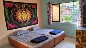 Ce lit se trouve dans un dortoir orné d'une peinture murale. dans l'établissement Bageecha B&B-Jal, à Alibaug