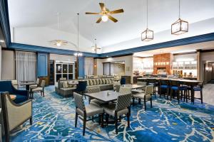 a hotel lobby with tables and chairs and a bar at Homewood Suites by Hilton Dallas-Lewisville in Lewisville