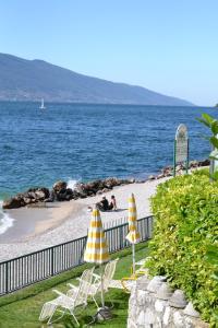 - deux chaises longues et des parasols sur une plage donnant sur l'océan dans l'établissement Residence San Luigi, à Limone sul Garda