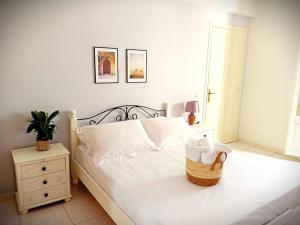 Un dormitorio con una cama blanca con una cesta. en Duka's Gardenhouse, en Skopelos Town