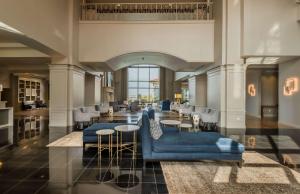 a lobby with a blue couch and tables and chairs at Hilton Dallas/Rockwall Lakefront Hotel in Rockwall