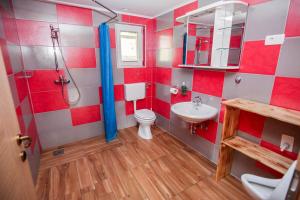uma casa de banho vermelha e branca com um WC e um lavatório em Apartmaji Pri Kozmavo - Little House em Bohinj