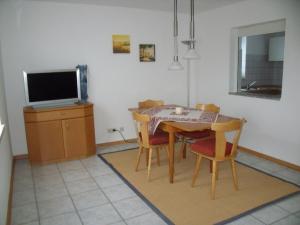 comedor con mesa, sillas y TV en Ferienwohnung am Reitplatz, en Neuried