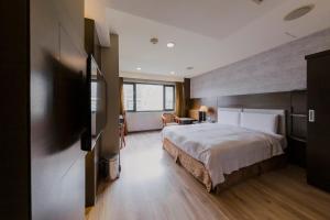 ein Hotelzimmer mit einem Bett und einem TV in der Unterkunft Shihzuwan Hotel – Kaohsiung Station in Kaohsiung