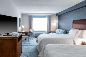 a hotel room with two beds and a flat screen tv at Hilton Garden Inn Arlington/Courthouse Plaza in Arlington