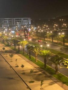 uma rua da cidade à noite com palmeiras e luzes de rua em Appartement Anir em Agadir