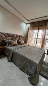um quarto com uma cama grande e uma janela grande em Appartement Anir em Agadir