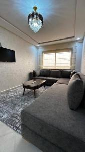 uma sala de estar com um sofá e um lustre em Appartement Anir em Agadir