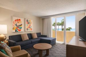 a living room with a couch and a room with a view of the beach at Embassy Suites by Hilton Deerfield Beach Resort & Spa in Deerfield Beach