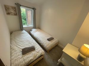 1 dormitorio con 2 camas y ventana en Tucked away house in Macclesfield, en Macclesfield