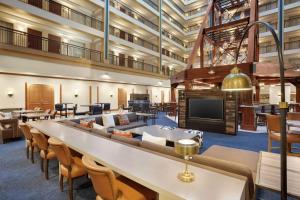 Embassy Suites by Hilton Denver International Airport في دنفر: غرفة كبيرة مع طاولات وكراسي ومدفأة كبيرة