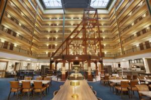 デンバーにあるEmbassy Suites by Hilton Denver International Airportのテーブルと椅子、シャンデリアが備わる広い客室です。