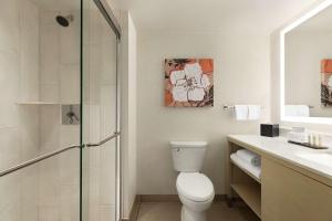 a bathroom with a toilet and a glass shower at Embassy Suites by Hilton Denver International Airport in Denver