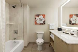 a bathroom with a toilet and a tub and a sink at Embassy Suites by Hilton Denver International Airport in Denver