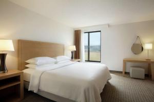 a hotel room with a white bed and a window at Embassy Suites by Hilton Denver International Airport in Denver
