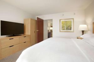 a bedroom with a large bed and a flat screen tv at Embassy Suites by Hilton Denver International Airport in Denver