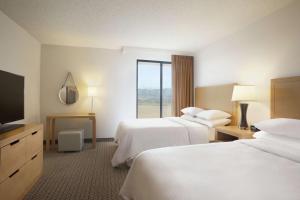 a hotel room with two beds and a flat screen tv at Embassy Suites by Hilton Denver International Airport in Denver