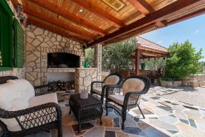 a patio with chairs and a stone fireplace at Trapula stone paradise in Maslinica